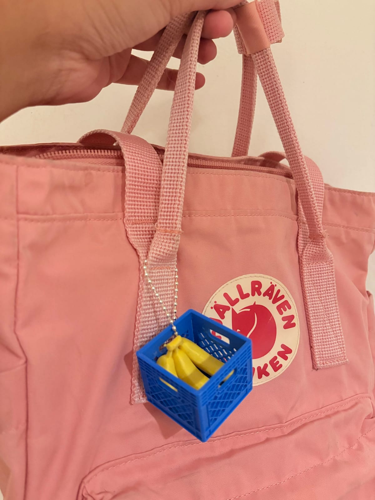 Blue fruit crate keychain clipped to a pink backpack