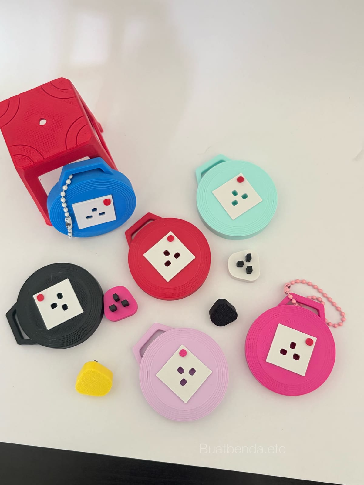 Round extension plug keychains in red, pink, mint and black with small plug tops