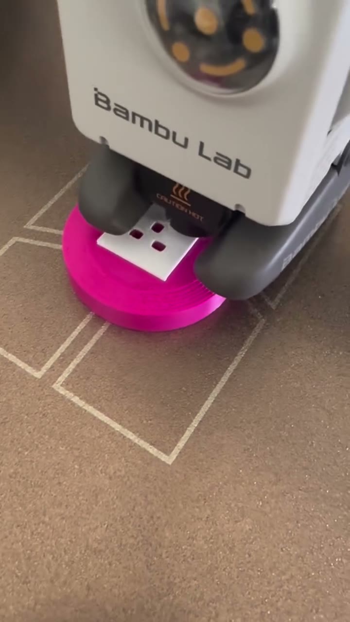 A pink round extension plug keychain being 3D printed on the printer bed