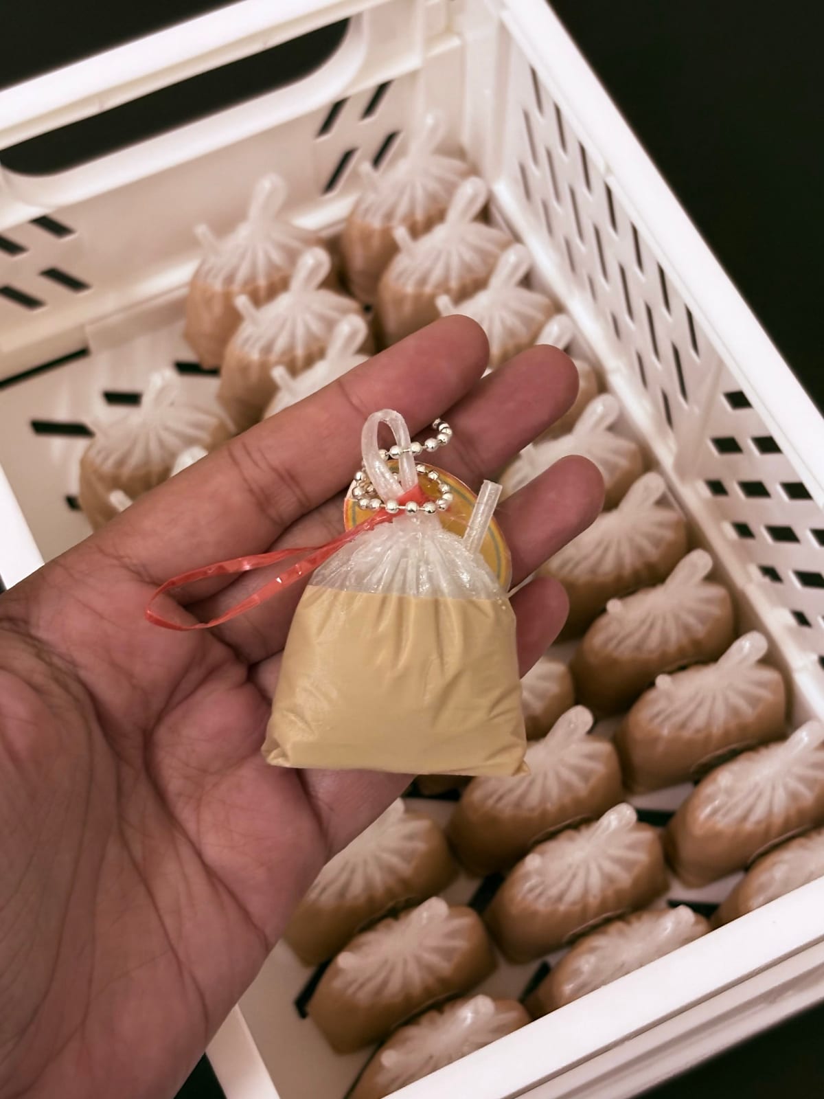 Tied drink bag keychain in teh ais brown held in a hand
